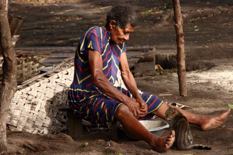 Eine ältere Frau raspelt Kokosnüsse