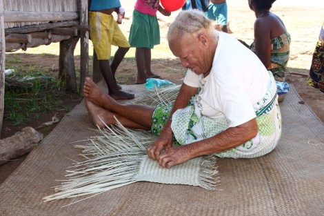 Alte Frau beim Flechten einer Matte